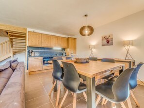 Eine moderne Küche mit Holzausstattung, ein Essbereich mit einem Holztisch und Stühlen sowie eine Treppe zu einer oberen Ebene.