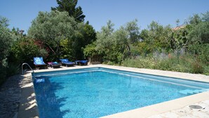 Una piscina rectangular con borde de azulejos, rodeada por una terraza de piedra.