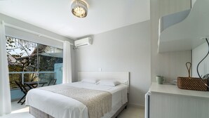 Une chambre avec un lit, une table de chevet sur laquelle se trouvent une tasse et des assiettes, une fenêtre donnant sur des arbres et un climatiseur fixé au mur.