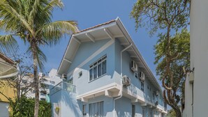 Un bâtiment à deux étages, doté d’une façade bleue, d’un balcon et d’une cour pavée.