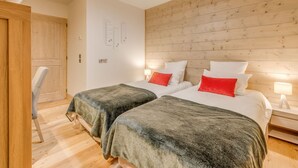 Une chambre d’hôtel moderne avec deux lits, des lambris en bois sur les murs et un luminaire au plafond en forme d’étoile.