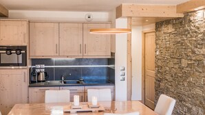 Une cuisine moderne avec des meubles en bois, un four encastré et un mur d’accent en pierre.