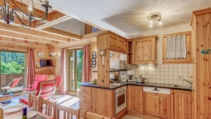 Ein Holzblockhaus-Innenraum mit Essbereich, Küche und Blick auf den Wald.