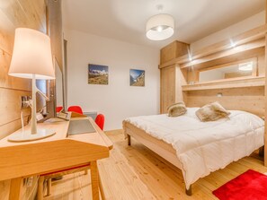 Camera da letto moderna con un letto in legno, una scrivania e una sedia. Due quadri decorano la parete.