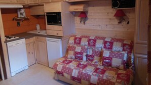 A compact kitchen with wooden cabinets, a microwave, a coffee maker, and a small dishwasher.