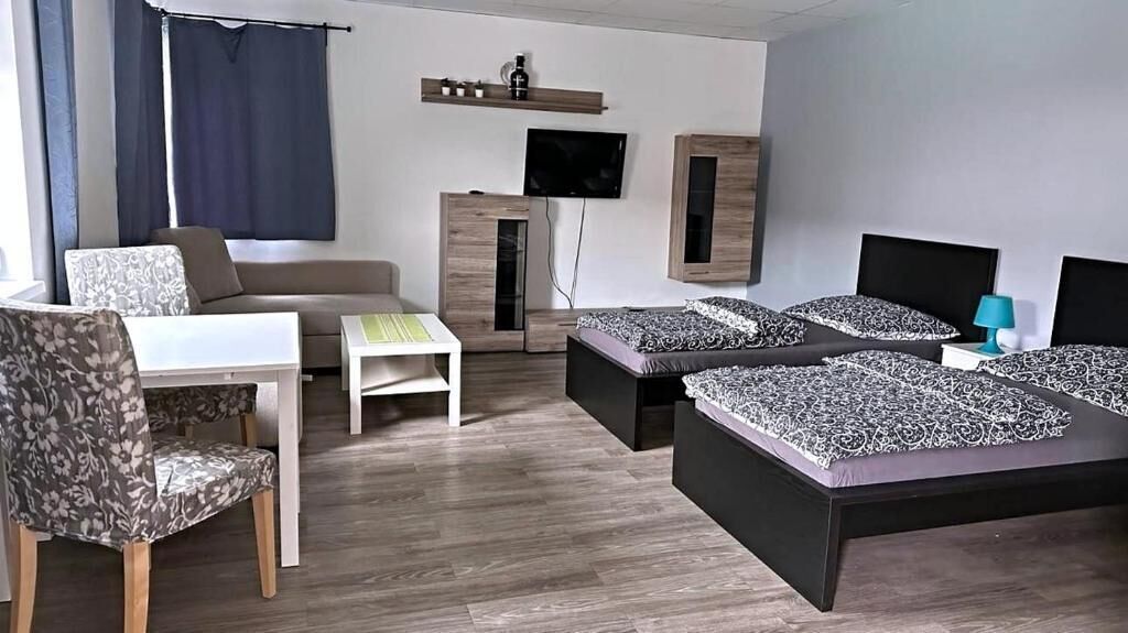 Una habitación de hotel moderna con sofá, dos camas, televisor y escritorio.