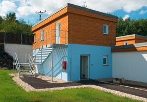 A modern building with a wooden exterior and a blue lower section, featuring a staircase and a small door. - Aparthotel DKS (Chomutov)