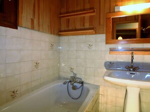 Un baño con bañera, lavamanos y armarios de madera.