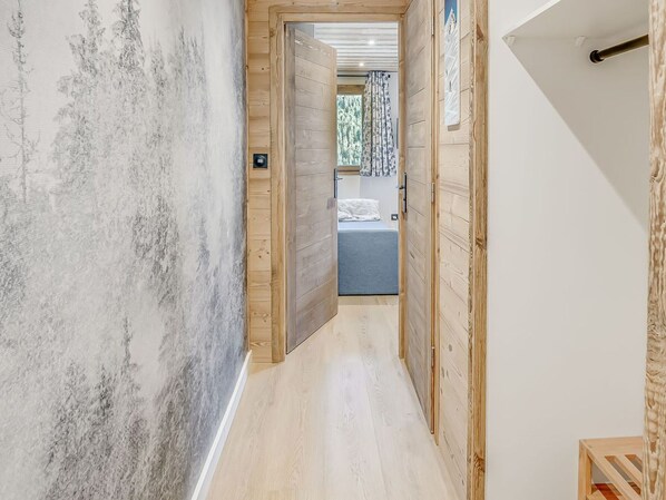 A hallway with wooden walls and a wooden door leading to a bedroom with a bed and a window. - Charming renovated 2-room for 4 with cable car access, Champagny (Champagny-en-Vanoise)