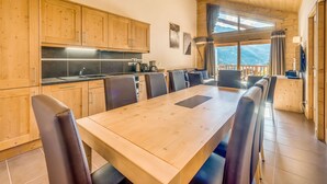 A wooden-paneled kitchen with a dining area, large windows, and a view of the mountains.
