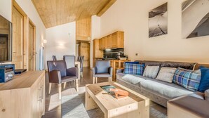 A modern living room with a wooden ceiling, a sofa, a coffee table, and a dining area with chairs and a table.