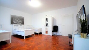 A bedroom with a bed, a wardrobe, a chair, a desk, and a mirror. - Ferienwohnung Maye Oberhausen (Oberhausen)