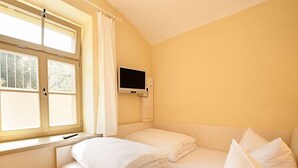 A room with a bed, a TV mounted on the wall, and a window with curtains. - FeWo Leibnizallee (Weimar)