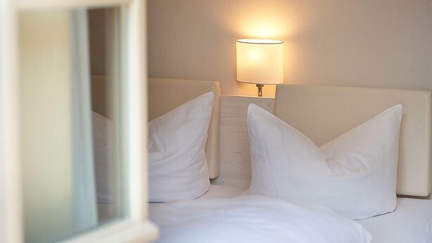 A hotel room with a bed, white pillows, and a bedside lamp. - FeWo Leibnizallee (Weimar)