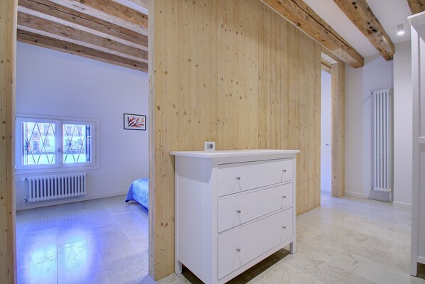 A room with a wooden ceiling, white walls, a white dresser, and a radiator. - GrandCanal-Red (Venice)