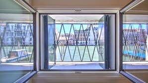 A window with a view of a river and buildings. - GrandCanal-Red (Venice)