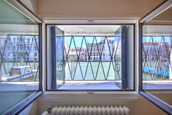 A window with a view of a river and buildings. - GrandCanal-Red (Venice)