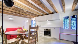 A modern kitchen with white cabinets, a built-in oven, and a window with decorative bars. - GrandCanal-Red (Venice)