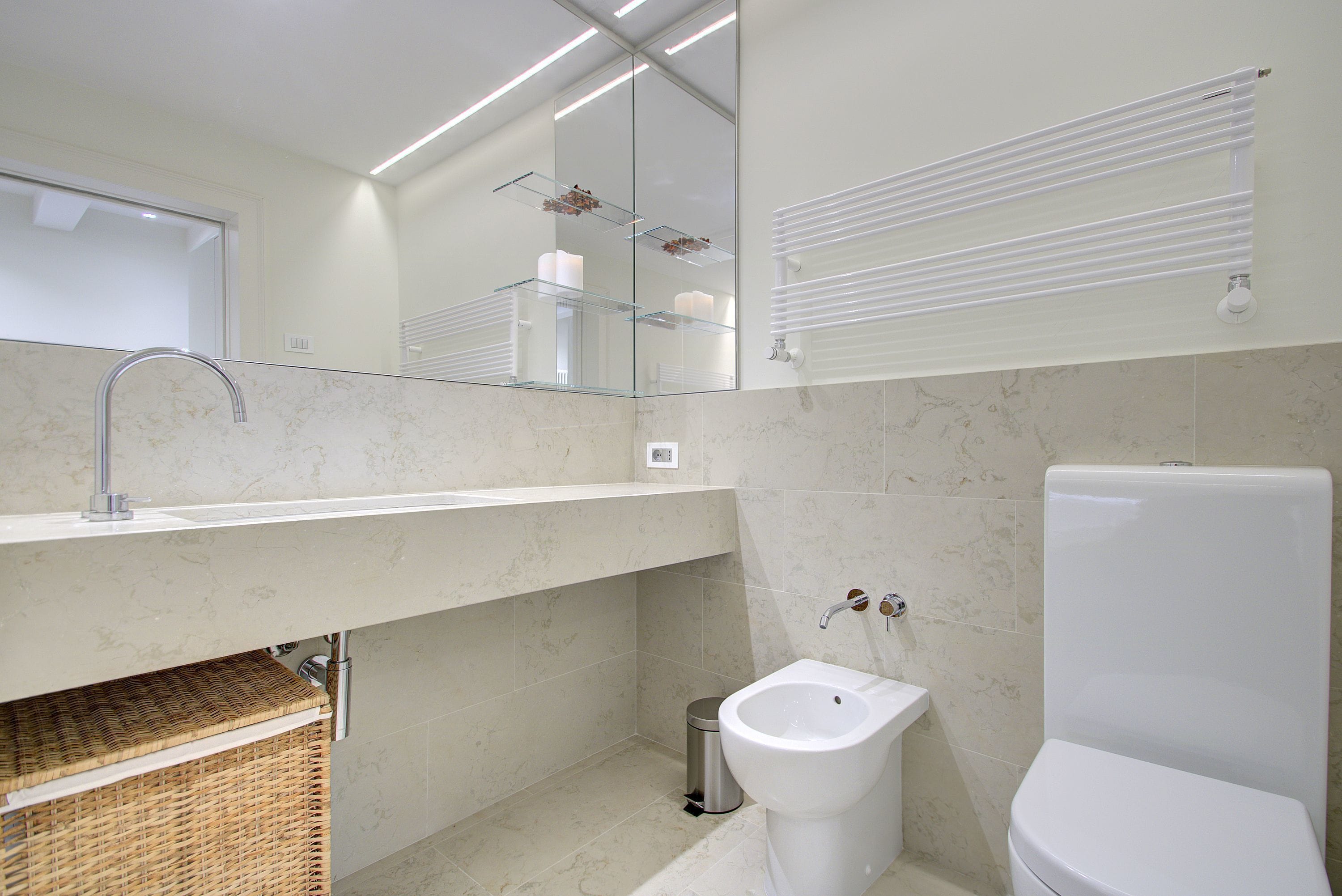 A modern bathroom with a glass shelf, a bidet, and a toilet.