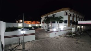 Una entrada porticada a un edificio con un camino de entrada pavimentado y coches aparcados.
