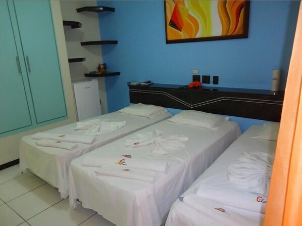 Habitación de hotel con dos camas, pared azul y un cuadro abstracto colorido.