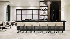 Een moderne keuken met een bar, voorzien van een marmeren aanrecht, barstoelen en een ingebouwde wijnkast.