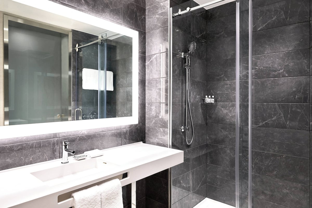 Un baño moderno con un lavabo blanco, un espejo grande y una ducha con mampara de vidrio.