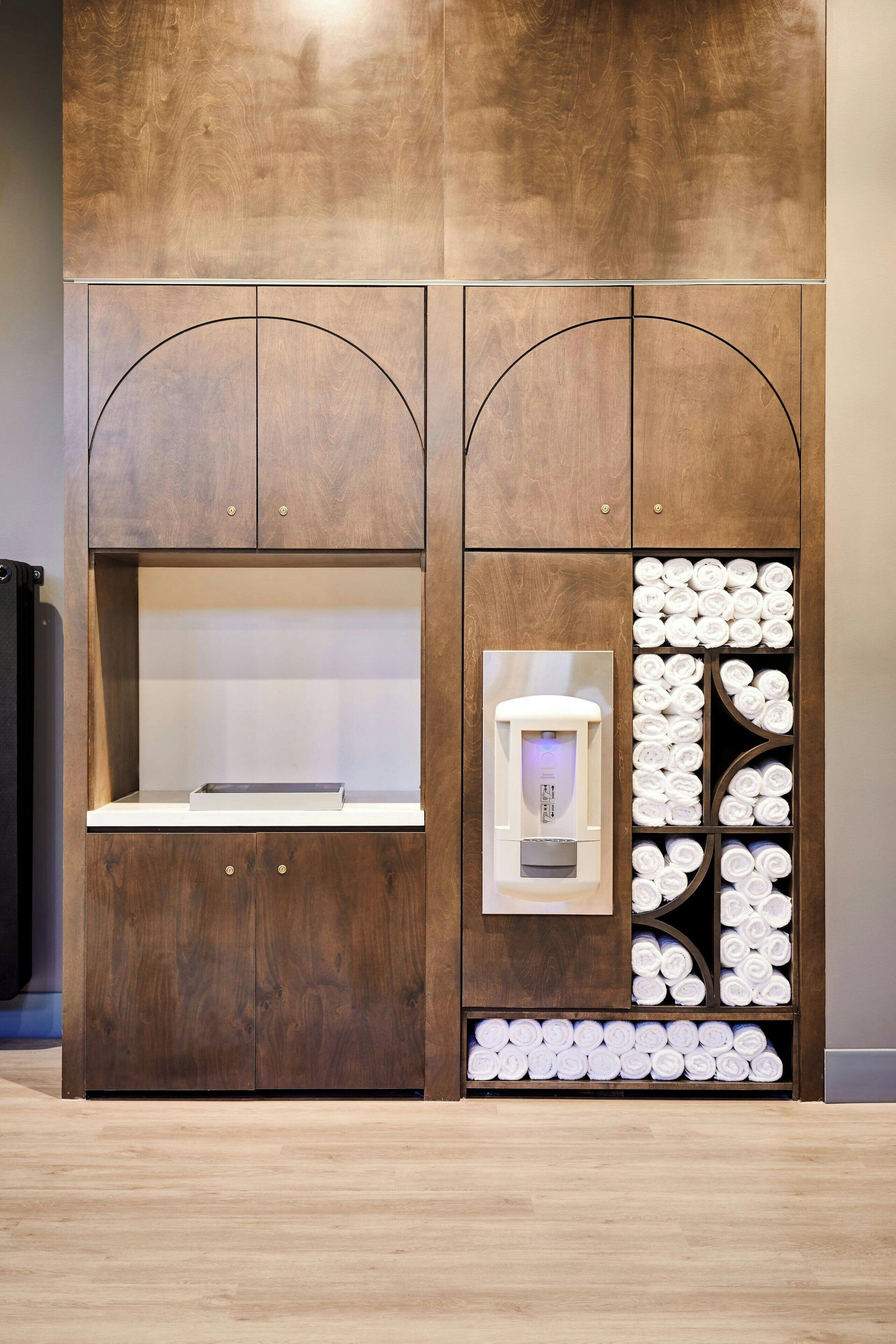 A wooden cabinet with a built-in water dispenser and towel storage.