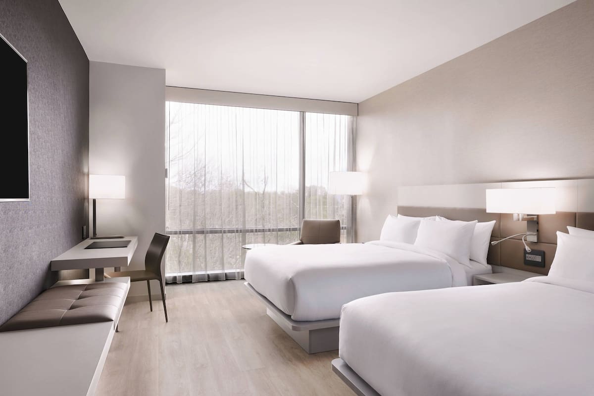 Una habitación de hotel moderna con dos camas, un escritorio y una silla.