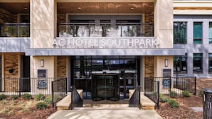 De ingang van AC Hotel Southpark met een draaideur, een hoge entree en een bord met de naam van het hotel.