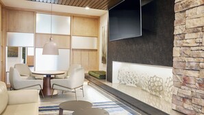 Ein modernes Wohnzimmer mit einem runden Tisch, zwei Sofas und einem großen Fernseher, der an einer Steinwand angebracht ist.