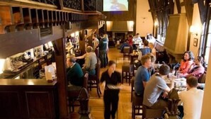 Uma área de bar com vigas de madeira e uma tela de televisão.