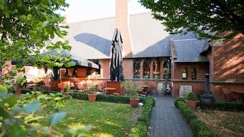 A brick building with outdoor seating, a pathway, and potted plants.