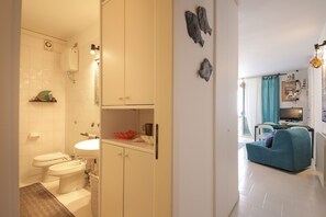 A compact living space with a bathroom, kitchenette, and a seating area. - Casa nel blu (Polignano a Mare)