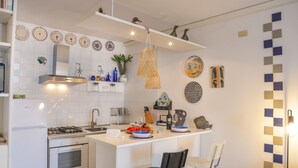 Una cocina moderna con armarios blancos, una isla central y una variedad de platos decorativos y elementos decorativos en la pared.