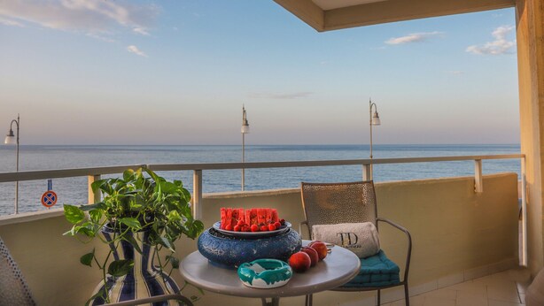 Un balcón con una mesa, una planta en maceta y vistas al mar.