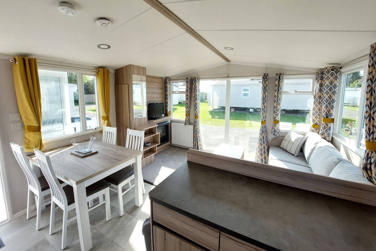 A spacious living area with a dining table, chairs, a sofa, and a television.