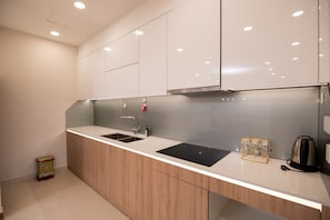 A modern kitchen with a white countertop, stainless steel sink, and wooden cabinets.