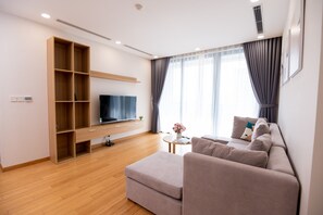 A modern living room with a wooden entertainment unit, a flat-screen TV, a beige sofa, and a small round table with a vase.
