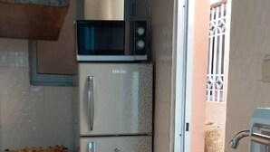 A kitchen with a stainless steel sink, a microwave, and a refrigerator. - BCBG KinShasa Apartment (Limete)