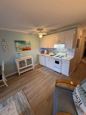 A compact kitchen with white cabinets, a built-in oven, and a ceiling fan.
