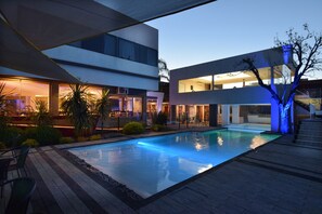 A modern pool area with a rectangular pool, surrounded by a stone deck and greenery. - Piazza Hotel (Villa Carlos Paz)