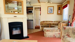 A compact living space with a fireplace, a dining table, and a sofa.