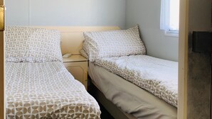 A bedroom with two beds, a window with a black valance, and a white ceiling with octagonal patterns.