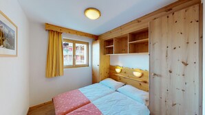 A bedroom with a bed, a window with curtains, a ceiling light, and wooden shelves. - Pracondu 2 401 - OUTDOOR & FUN  apartment 6 pers (Haute-Nendaz)