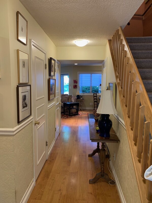 Stunning hallway leads to a dining area with a wooden staircase, table, and chair.