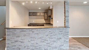 A kitchen with a stone island, recessed lighting, and wooden cabinets.