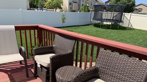 A deck with wicker furniture and a trampoline in the background.