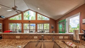 A kitchen with a granite countertop, a sink, and a ceiling fan. - Four Bears Bungalow (Ruidoso)