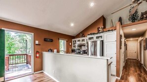 A spacious kitchen with a central island, wooden flooring, and a view of the outdoors. - Four Bears Bungalow (Ruidoso)